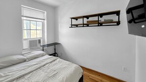 Une chambre à coucher avec un lit, une fenêtre, un radiateur et une étagère.