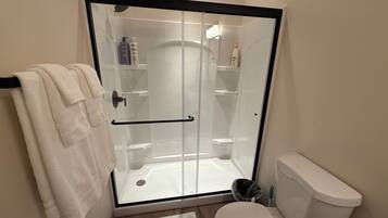 A bathroom with a glass-enclosed shower, a toilet, and a towel rack.
