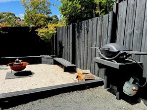 A backyard with a barbecue grill, a fire pit, and a gas cylinder. - Little Red Gate Urban Retreat (Kingston)