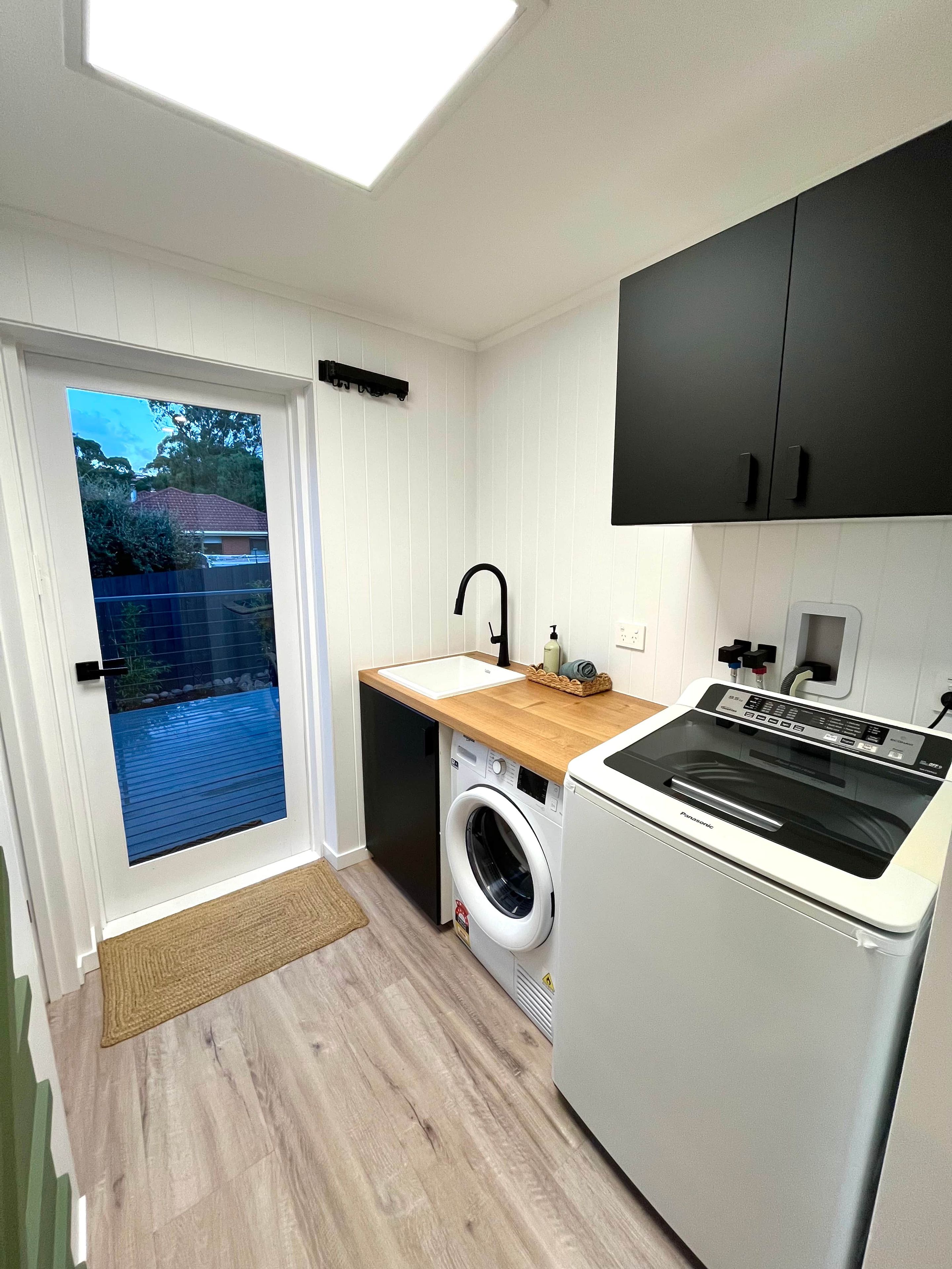 A compact kitchen with a washing machine, a sink, and a built-in oven.