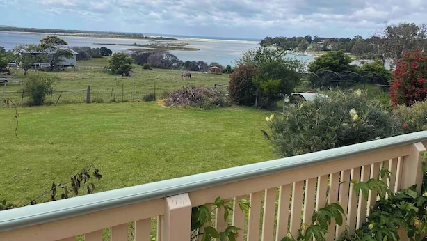 A grassy area with a view of a body of water and distant land. - The Cottage at Raheen (Mallacoota)