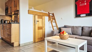 A modern living space with a kitchen, a loft bed, a white coffee table, and a red sports jersey on the wall. - Domaine des Reines D10 by Interhome (Nendaz)