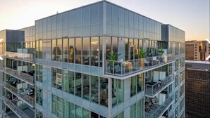 En modern byggnad med fasad av glas, flera våningar och balkonger, som erbjuder en fri utsikt över den omgivande stadsbilden.