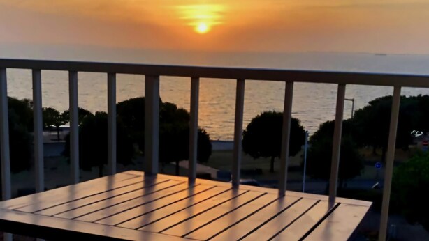 Un balcon avec vue sur le coucher de soleil sur l’eau.