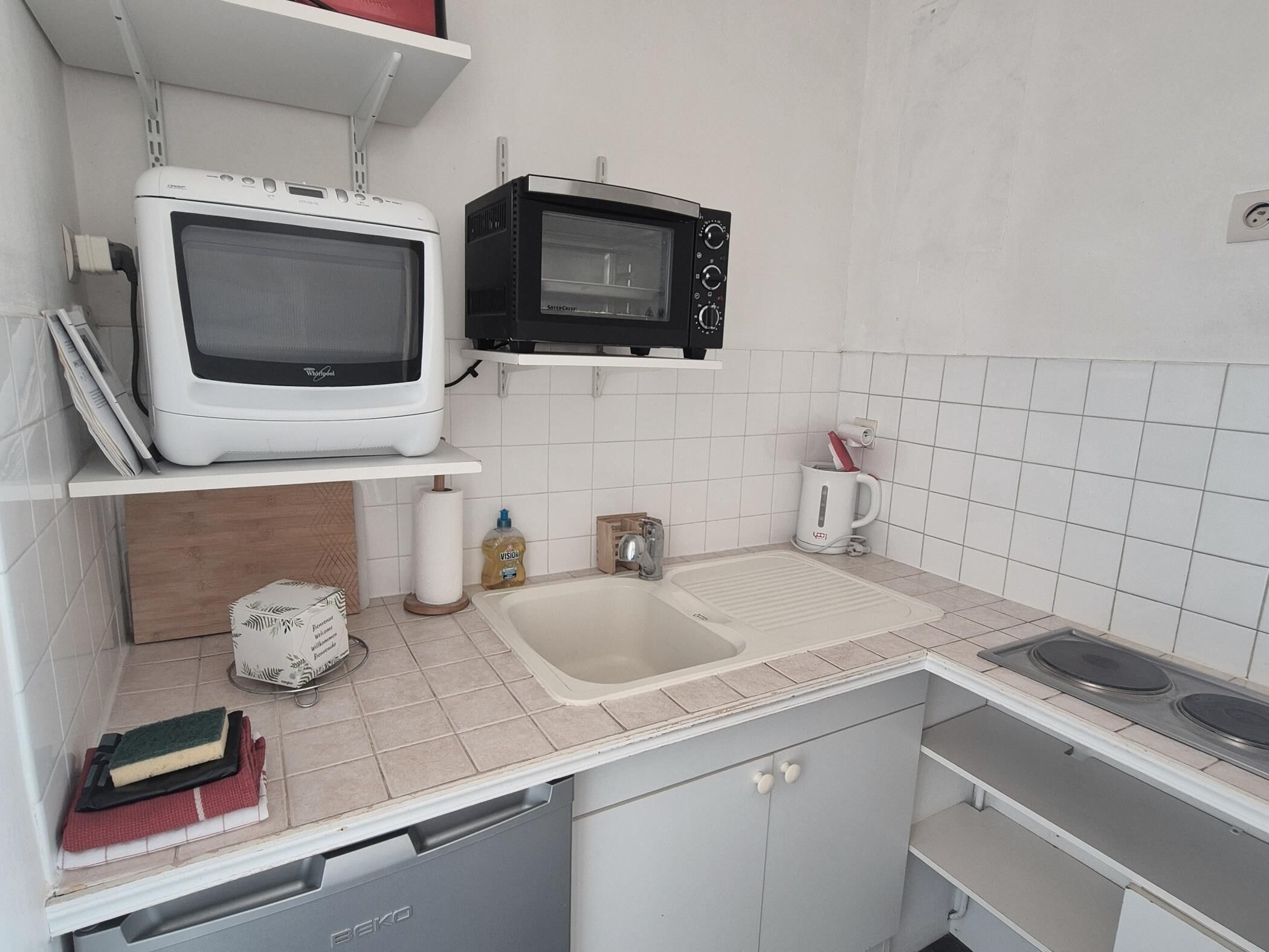 Une cuisine équipée d’un four à micro-ondes blanc, d’un four à micro-ondes noir, d’un évier et d’une cuisinière.