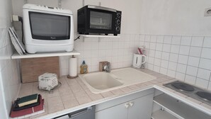 Une cuisine équipée d’un four à micro-ondes blanc, d’un four à micro-ondes noir, d’un évier et d’une cuisinière.