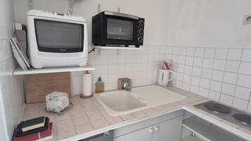 Une cuisine équipée d’un four à micro-ondes blanc, d’un four à micro-ondes noir, d’un évier et d’une cuisinière.