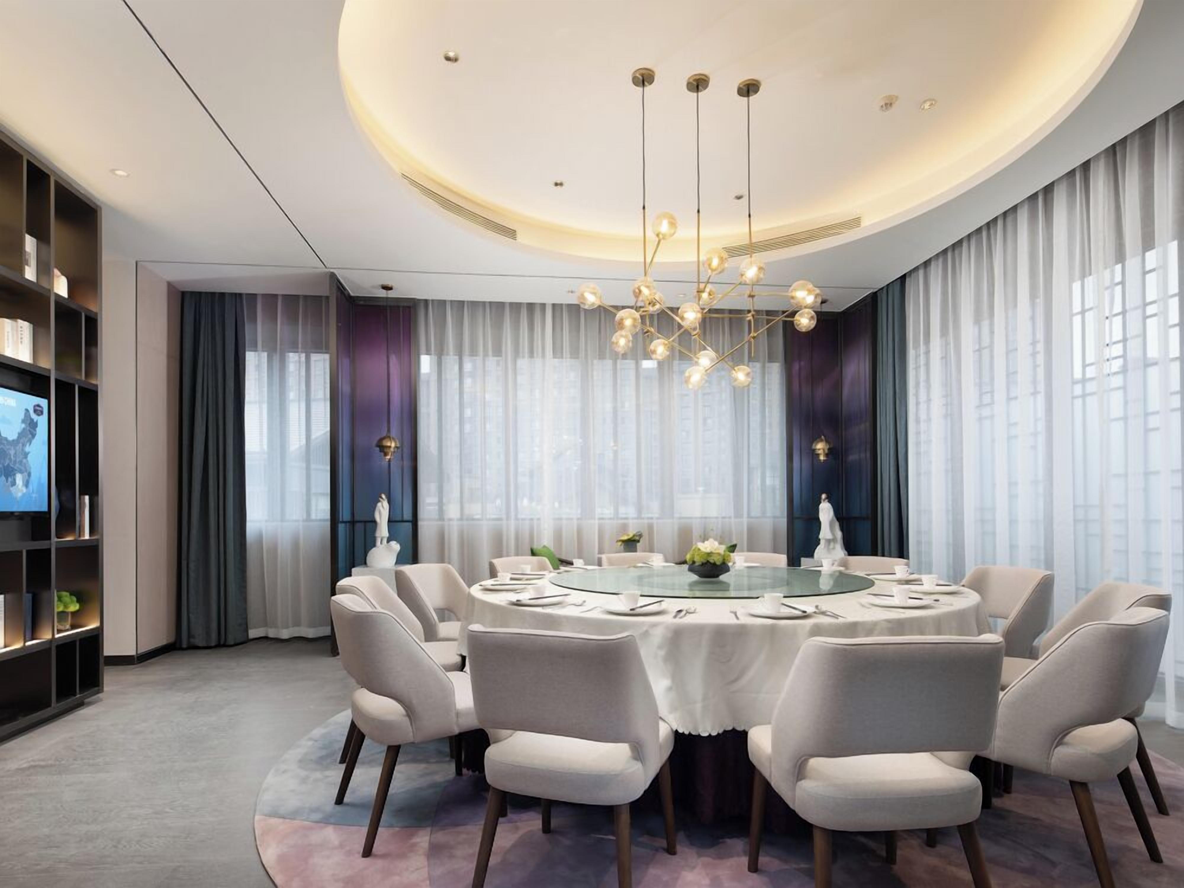 Une salle à manger moderne avec une table ronde, des chaises confortables et un lustre.