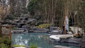 A tranquil garden with a clear pond, large rocks, and a waterfall. - Hampton by Hilton Emeishan Scenic Area (Leshan)