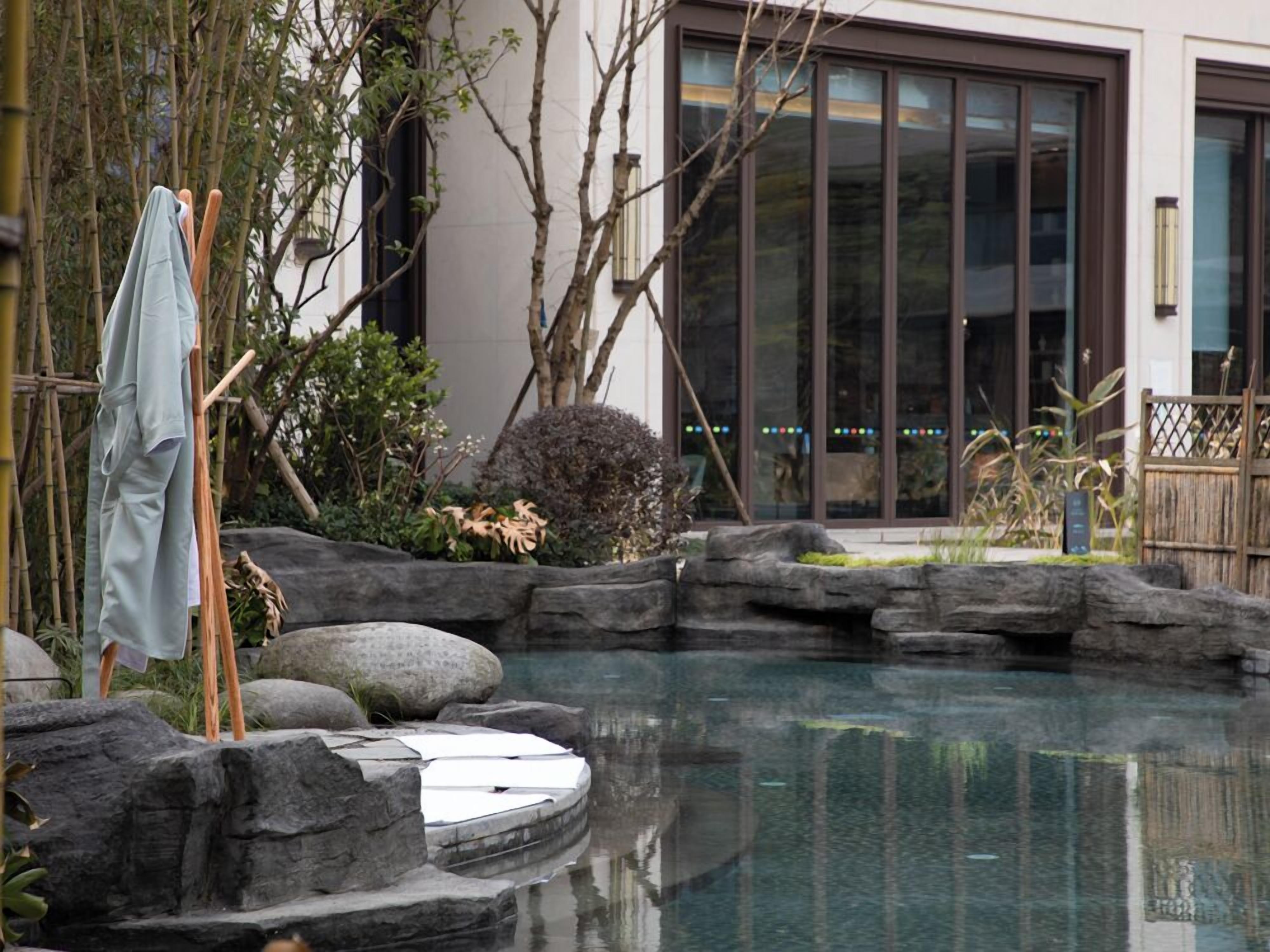 A modern house with a swimming pool surrounded by rocks and plants.