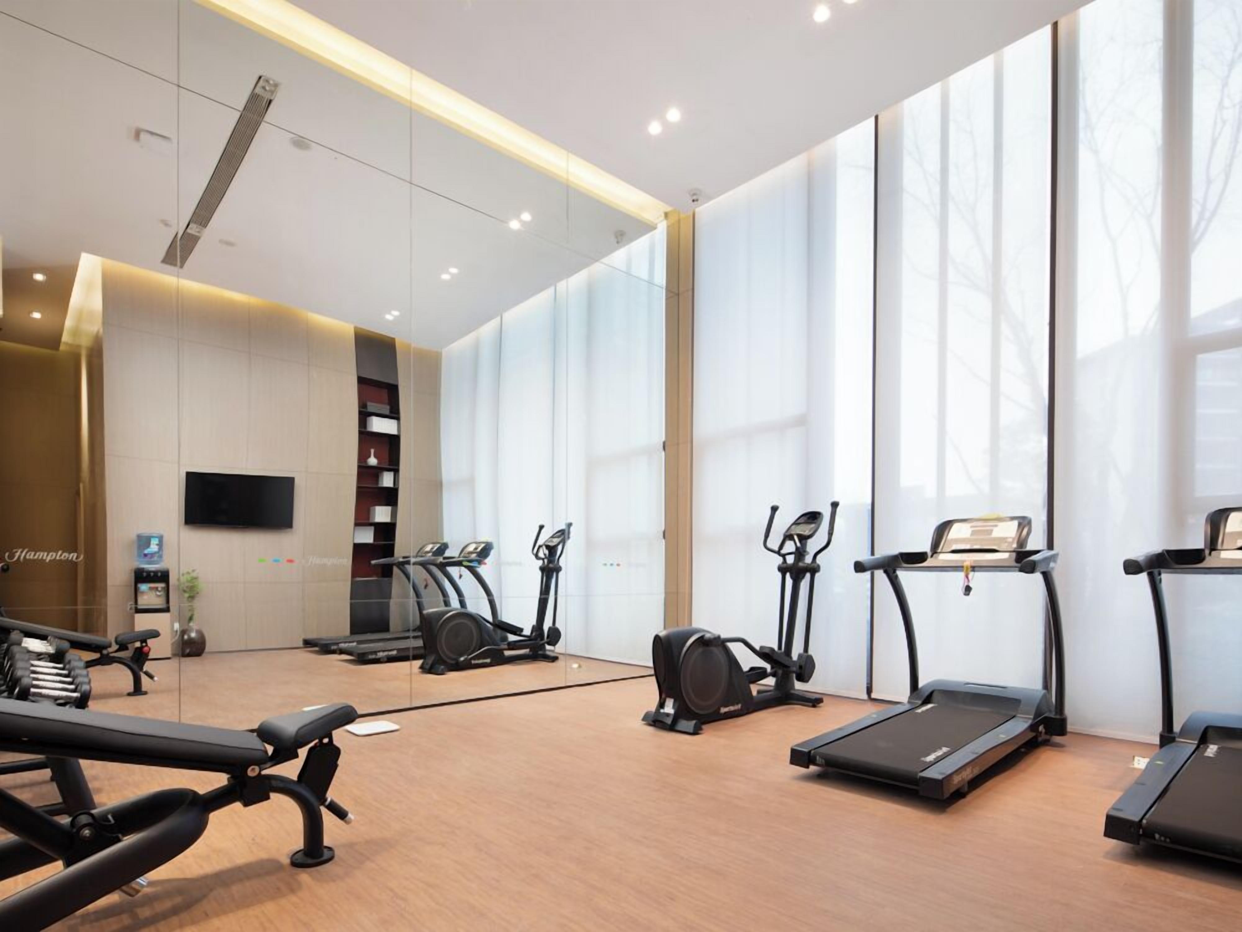 A modern gym with treadmills, elliptical machines, and weight benches.