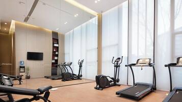 A modern gym with treadmills, elliptical machines, and weight benches.