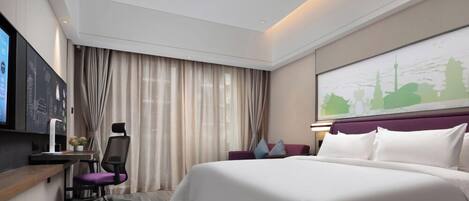 A modern hotel room with a large bed, a desk with a chair, a television, and a cityscape artwork on the wall.