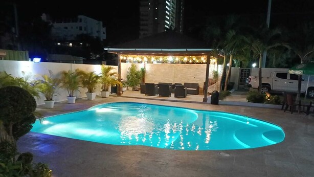 Ein Schwimmbecken mit überdachter Sitzgelegenheit und Topfpflanzen.