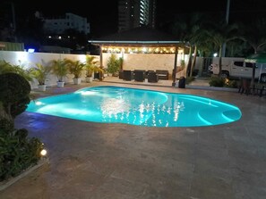 Ein Schwimmbecken mit überdachter Sitzgelegenheit und Topfpflanzen.