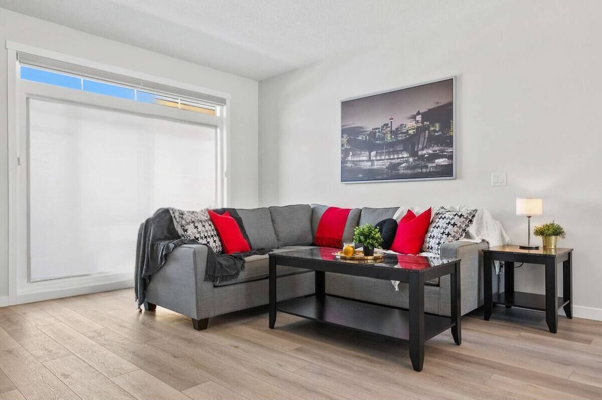 A modern living room with a grey sectional sofa, a black coffee table, and a small side table with a lamp.