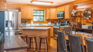 Una cocina moderna con armarios de madera, electrodomésticos de acero inoxidable y una isla central con taburetes.