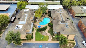 An aerial view of a residential area with a swimming pool surrounded by houses, a parking lot, and a street. - Houston Galleria Suite 
Modern Rental 5 mins from the Galleria Mall (Houston)