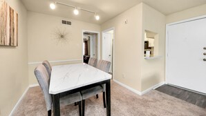 A dining area with a marble table and cushioned chairs, a ceiling light fixture, and a door leading to a kitchen. - Houston Galleria Suite 
Modern Rental 5 mins from the Galleria Mall (Houston)