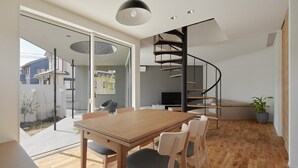 A modern interior with a spiral staircase, a dining area with wooden furniture, and a sliding glass door leading to an outdoor space.
