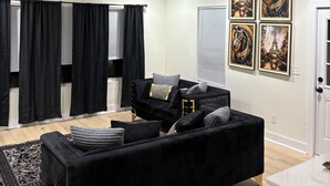 A modern living room with a black sofa, a ceiling fan, and artwork on the wall.