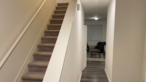 A staircase with carpeted steps leading to a room with a wooden floor.
