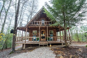 Eine Holzhütte mit Veranda, umgeben von Bäumen.