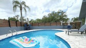 Une piscine avec un flotteur gonflable aux couleurs vives, des chaises longues et une clôture en bois.