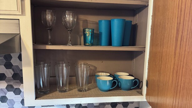 Eine Küche mit Mikrowelle, Kaffeemaschine und einem Schrank mit verschiedenen Gläsern und Tassen.