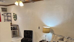 Ein Schlafzimmer mit Bett, Sessel, Nachttisch, Lampe, Deckenventilator und Teppich.