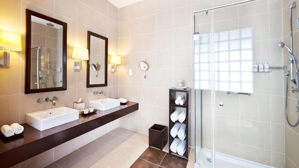 A modern bathroom with two sinks, a glass shower enclosure, and a vanity with a mirror. - Adaaran Prestige Water Villas with Premium All-Inclusive (Meedhupparu)
