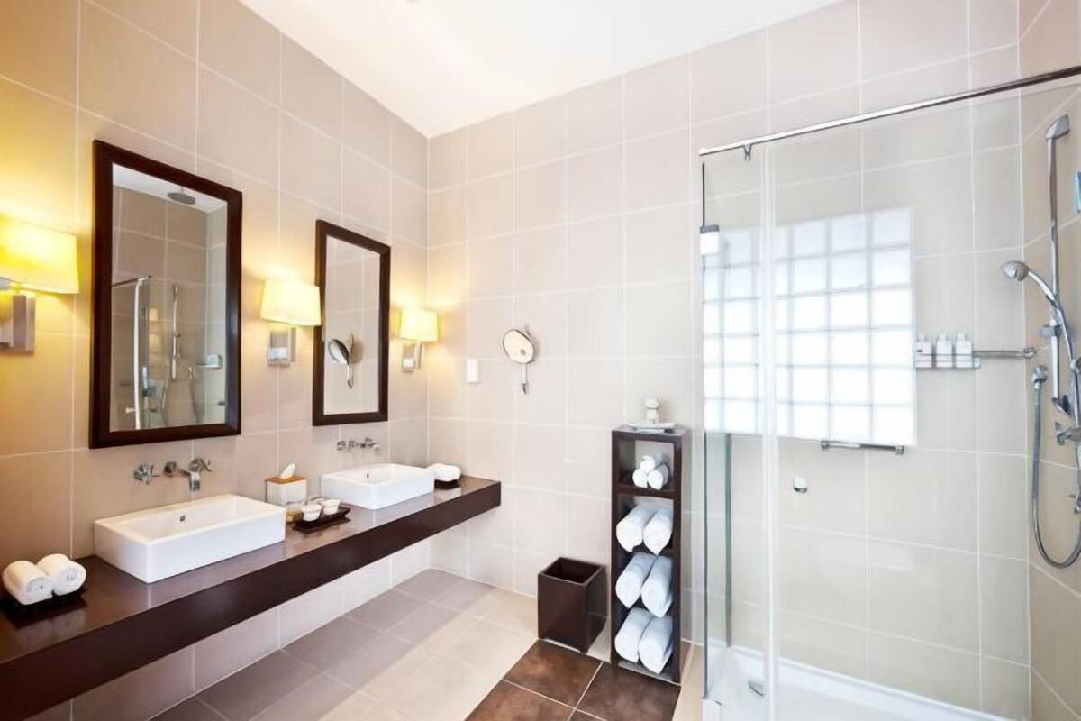 A modern bathroom with two sinks, a glass shower enclosure, and a vanity with a mirror.