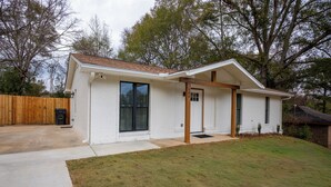 A single-story house with a front porch, a garage, and a well-maintained lawn. -  The Scholar's Retreat (Tuskegee)