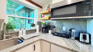 A modern kitchen with a built-in microwave, coffee maker, toaster, and a window with a view of trees. - Romantic Lakefront Getaway with Balcony near Downtown Orlando (Orlando)