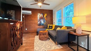 A modern living room with a sofa, a coffee table, a TV, and a ceiling fan. - Romantic Lakefront Getaway with Balcony near Downtown Orlando (Orlando)