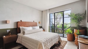 Une chambre avec un grand lit, une table de chevet, une fenêtre donnant sur un paysage verdoyant et une plante en pot.