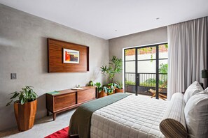A modern bedroom with a large bed, a wooden dresser, multiple potted plants, and a large window with curtains. - ALMA Surf Lodge Terrace Queen (Corral del Risco)