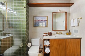 A bathroom with a shower, toilet, sink, and wooden cabinet with towels. - ALMA Surf Lodge Terrace Queen (Corral del Risco)