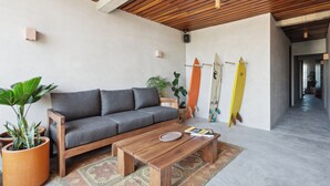 A modern living room with a grey sofa, wooden coffee table, and potted plants. - ALMA Surf Lodge Terrace Queen with View (Corral del Risco)