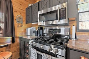 Una cocina moderna con electrodomésticos de acero inoxidable, gabinetes de madera y encimera de piedra.