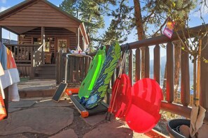Una baita di legno con un portico, un kayak e una tavola da paddleboard appoggiati a una ringhiera.