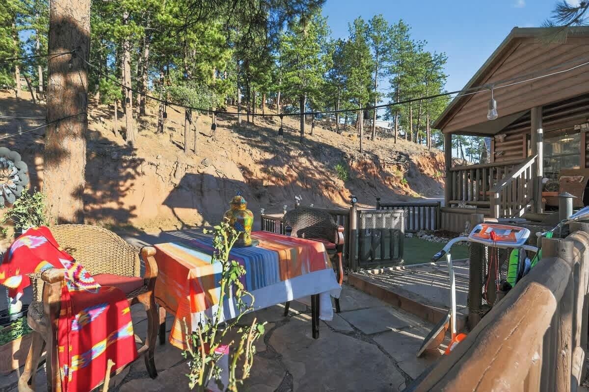 Een houten vakantiehuisje met een terras, omgeven door bebossing.