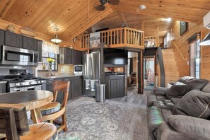 Interior acogedor de una cabaña con cocina, comedor y sala de estar con sofá.