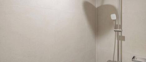 Ducha moderna con cabezal de ducha de mano y panel de control en la pared.
