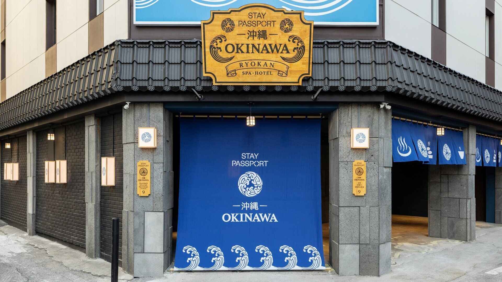 Ingresso di un hotel in stile Ryokan, con una grande porta blu e un cartello che indica che è un hotel passport.