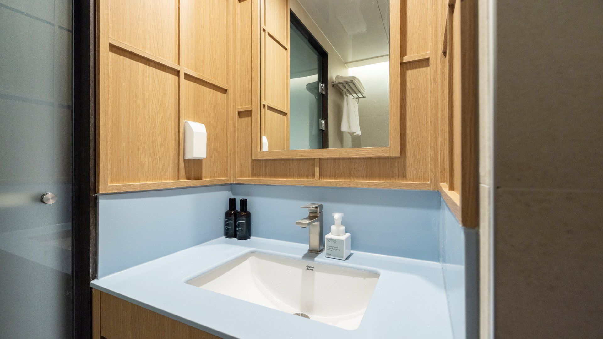 A bathroom with wooden cabinets, a white sink, and a mirror.