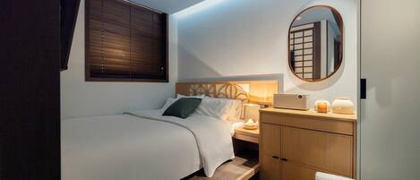 Een kleine hotelkamer met een eenpersoonsbed, nachtkastje en een klein houten kastje.