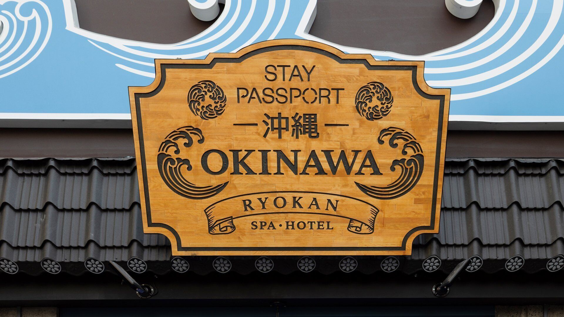 A wooden sign with "Okinawa Ryokan Spa-Hotel" written on it.