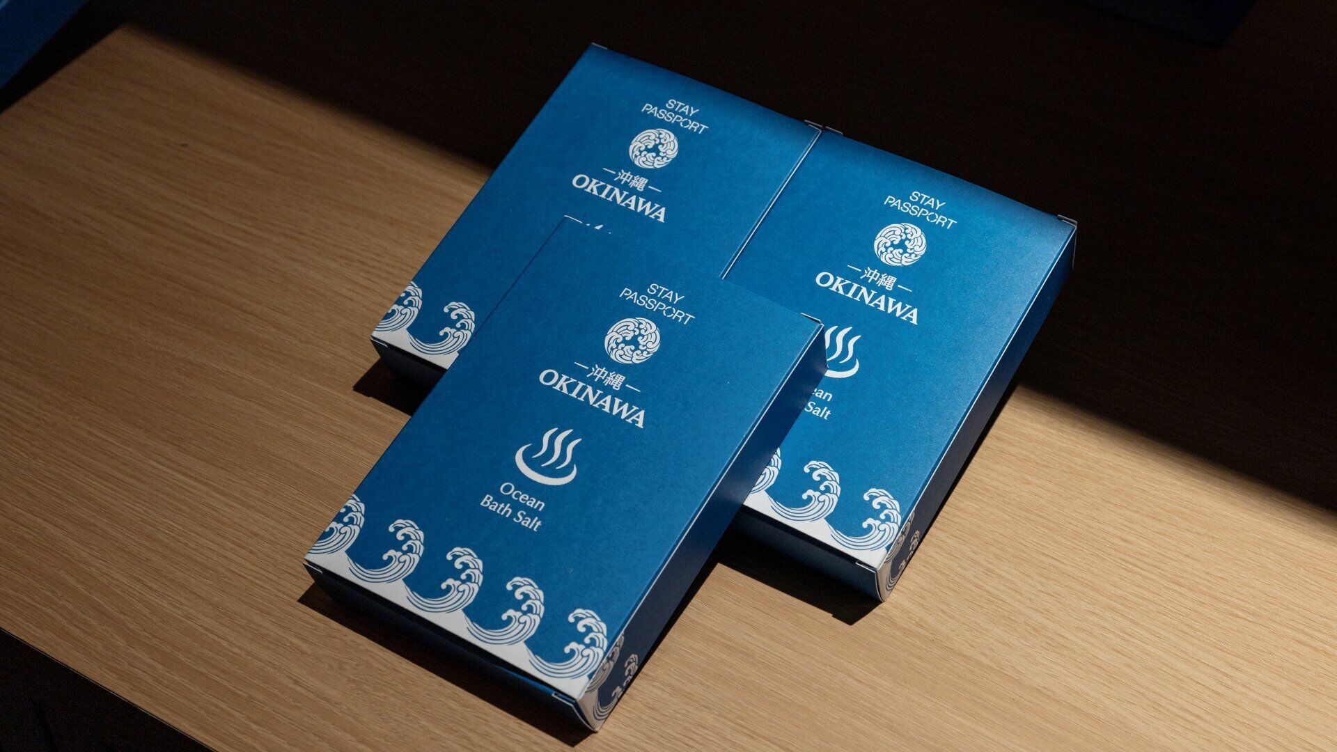 Two blue boxes with "STAY PASSPORT" and "OKINAWA" text, placed on a wooden surface.