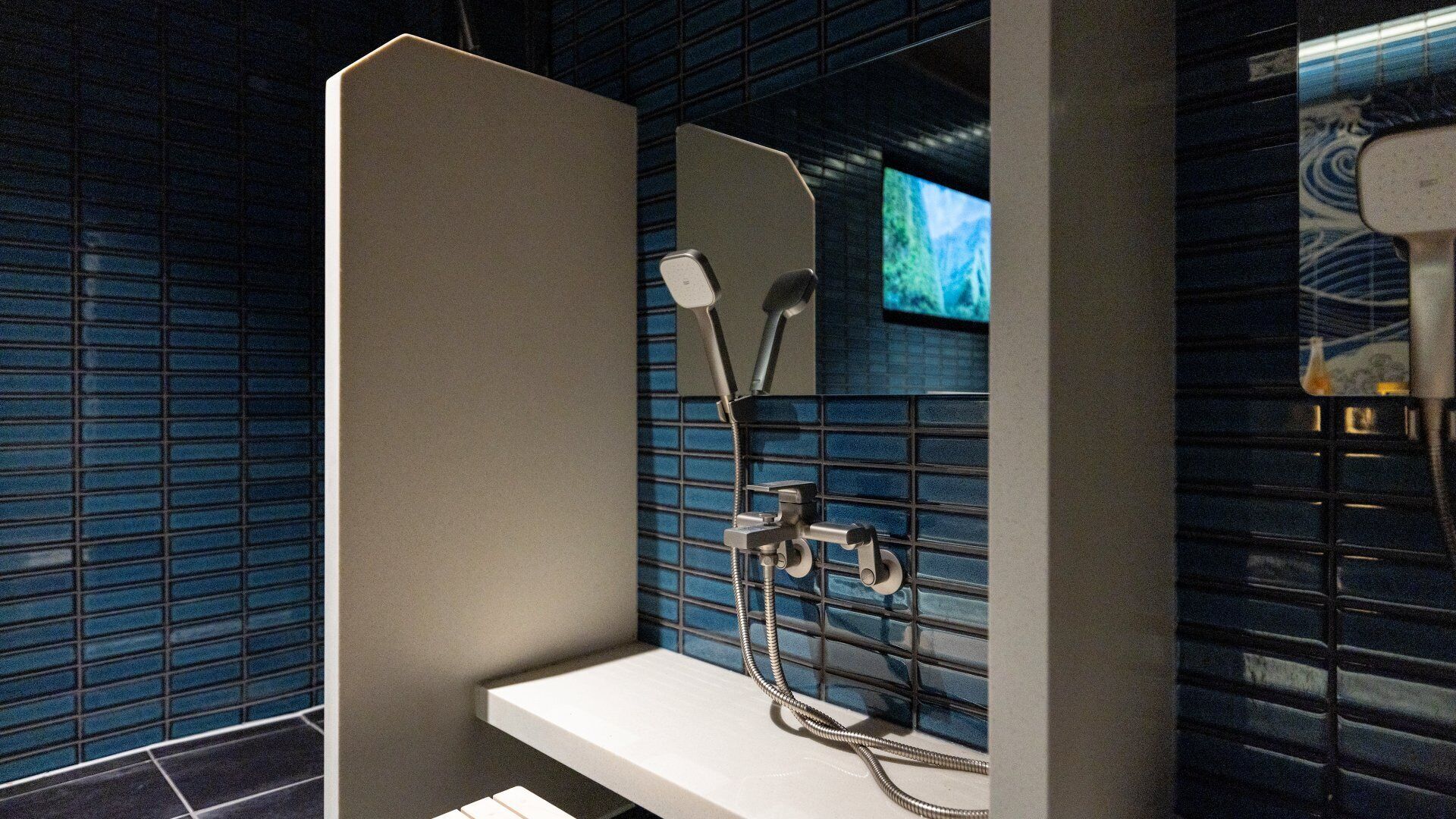 A modern bathroom with a shower enclosure, a sink, and a television mounted on the wall.